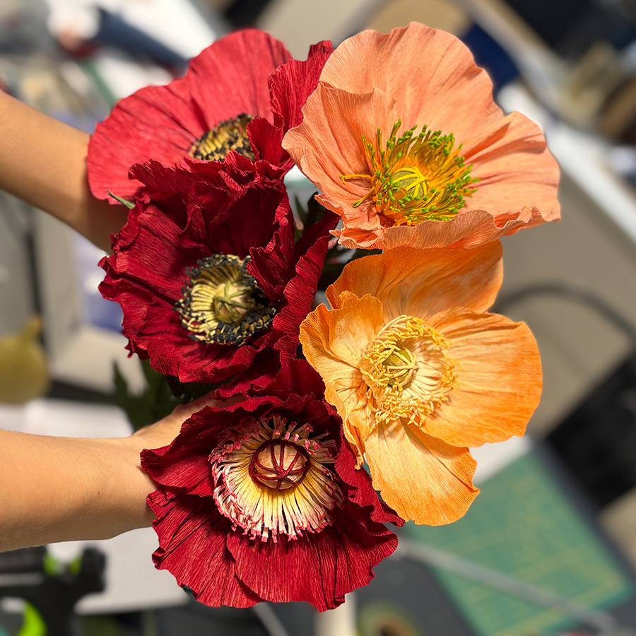 gros plan sur cinq fleurs en papier colorées dans l'atelier de Stéphane Buyens